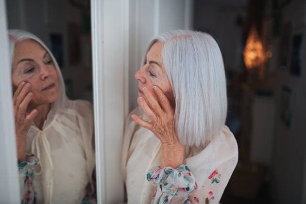 Portrait of beautiful senior woman standing in front mirror, making phone call. Portrait of beautiful senior woman standing in front mirror and making phone call. model released