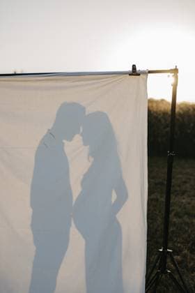 Schwangere, junge Frau mit Partner als Silhouette hinter Leintuch Pregnant young woman with partner in silhouette behind a sheet Copyright: imageBROKER MichaelaxBegsteiger ibxbeg14767761.jpg ,model released, Symbolfoto ,property released