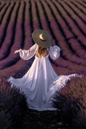 Here s a title following your specifications: Lavender Fields, Provence France: Woman in White Dress, Summer Photo Shoot, Aesthetic Imagery Here s a caption that describes the image in under 150 characters: Woman in white flowing dress and wide-brimmed hat twirls in a vast purple lavender field. Sunlight bathes the scene., model released, , 63322054.jpg RECORD DATE NOT STATED