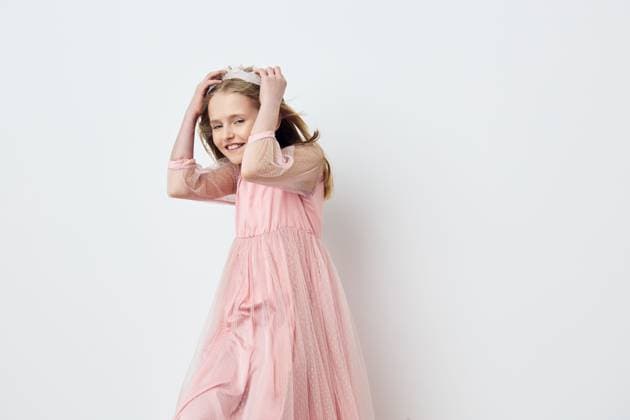 Smiling girl in a pink dress with a playful pose against a minimalist white background, showcasing joy and youthfulness in a studio setting A joyful young girl in a flowing pink dress poses playfully against a clean white backdrop, radiating happiness and innocence Perfect for kids fashion or cheerful themes, model released, , 96310106.jpg RECORD DATE NOT STATED