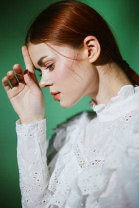 Portrait of a young woman in a white lace dress with a thoughtful expression against a green background, showcasing elegance, emotion, and seasonal style A profile portrait of a young woman in a white lace dress, displaying a contemplative emotion against a vibrant green background The image emphasizes elegance and beauty with seasonal appeal, model released, , 96310490.jpg RECORD DATE NOT STATED