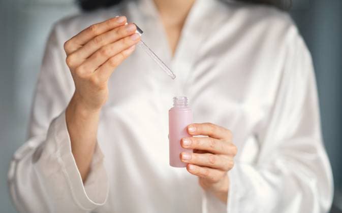 Young woman pampering herself with skincare in a stylish bathroom In a modern bathroom, a young Caucasian woman with brunette hair enjoys a skincare routine. She carefully uses a dropper to apply a gentle serum, embracing self-care and relaxation., model released, , 63613228.jpg RECORD DATE NOT STATED