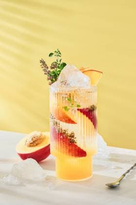 Kalter erfrischender Pfirsich-Limetten-Cocktail garniert mit Minze und Thymianblättern im Glas auf gelbem hellem Hintergrund. Sommergetränke für zu Hause. Kalter erfrischender Pfirsich-Limetten-Cocktail garniert mit Minze und Thymianblättern im Glas auf gelbem hellem Hintergrund. Sommergetränke für zu Hause. (License=RF) Copyright: xZoonar.com KatsiarynaxHuravax 23913321