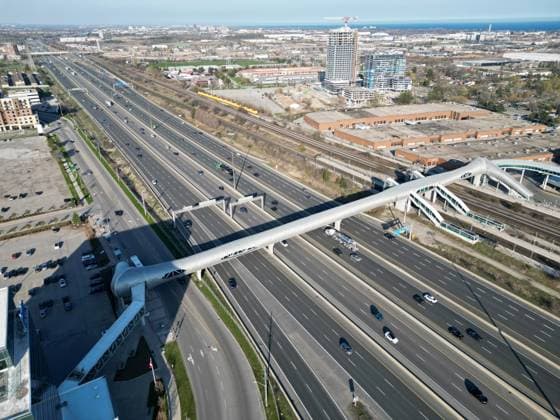 World’s Longest Enclosed Pedestrian Bridge PICKERING, ONTARIO - APRIL 27 : Aerial view of cars and trucks pass under Pickering pedestrian bridge on Highway 401 in Pickering, Ontario on April 27, 2023. Guinness World Record holder Pickering pedestrian bridge, located 45 minutes east of Toronto, in the City of Pickering, Ontario, Canada was completed in September 2018. The 250-meter bridge stretches across 14 lanes of Highway 401, six active railway tracks, and a two-lane local road. Additionally, it features nearly 300 LED lights that illuminate it beautifully at night. Ontario Canada. Editorial use only. Please get in touch for any other usage. Copyright: x2025xAnadoluxMertxAlperxDerviÅüx