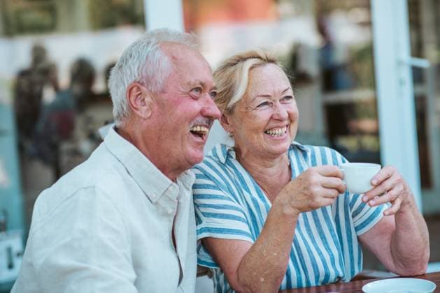 Smiling elderly couple enjoying coffee together in the garden. Smiling elderly couple enjoying coffee together in the garden, sharing joyful moment. model released