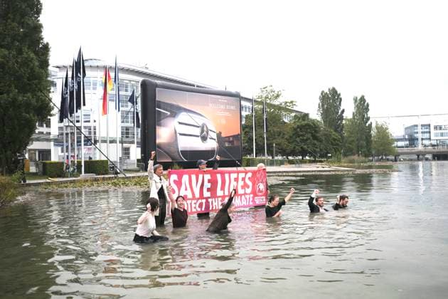 Extinction Rebellion Protest vot IAAMobility Prostestveranstaltung von Extinction Rebellion gegen die IAA Mobility auf dem Messegelände München. Die Protestierenden haben ein Banner gehisst, sie selbst stehen halb im Wasser des Sees vor dem Haupteingang der Messe München. Im Hintergrund ist ein überdimensionales Werbeplakat von Mercedes Benz zu sehen. München *** Extinction Rebellion Protest vot IAAMobility Protest event by Extinction Rebellion against the IAA Mobility at the Munich Exhibition Center The protesters have hoisted a banner, they themselves are standing half in the water of the lake in front of the main entrance to the Munich Trade Fair Center An oversized Mercedes Benz advertising poster can be seen in the background M RECORD DATE NOT STATED