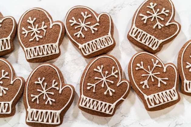 IMAGO Creative, Weihnachten, Food, Backen, Lebkuchen Beautifully Decorated Mitten Cookies with Royal Icing Designs Close-up of beautifully decorated mitten-shaped gingerbread cookies featuring intricate white royal icing designs, arranged on a marble surface., 94616066.jpg RECORD DATE NOT STATED