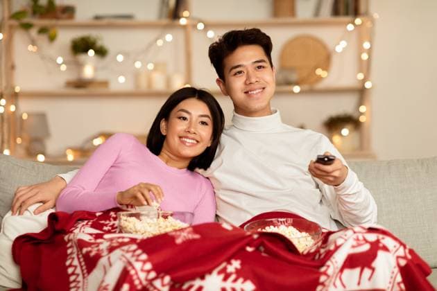 Asian Couple Watching Christmas Movies On TV Sitting At Home Asian Couple Watching Christmas Movies On TV Eating Popcorn Sitting On Sofa At Home, Covered With Blanket. Family Enjoying Xmas Eve And Holidays Television Show In Cozy Living Room Concept, model released, , 96733472.jpg RECORD DATE NOT STATED
