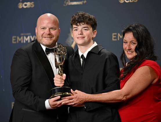 British actor Owen Cooper (C) holds the Emmy for Outstanding Supporting Actor in a Limited or Anthology Series or Movie for Adolescence, alongside his parents Noreen (R) and Andy Cooper (L) backstage during the 77th annual Primetime Emmy Awards at the Peacock Theater in Los Angeles on Sunday, September 14, 2025.  LAP20250914194 CHISxCHEW