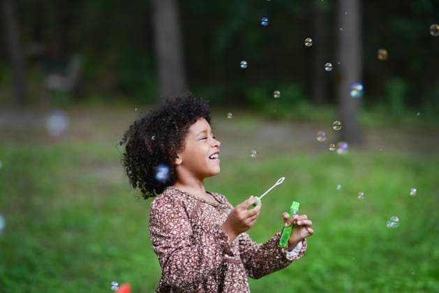 Laughing girl blows bubbles in grassy outdoor area. United States, Florida, Floral City CR_YWQX250910A-1811574-01 ,model released, Symbolfoto