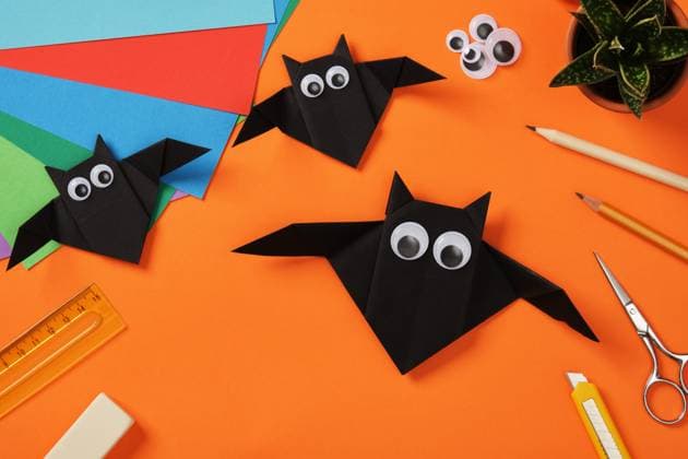 Three handmade black origami bats with googly eyes on a bright orange background surrounded by colorful paper sheets and crafting tools Three handmade black origami bats with googly eyes on a bright orange background surrounded by colorful paper sheets and crafting tools, 97686048.jpg RECORD DATE NOT STATED
