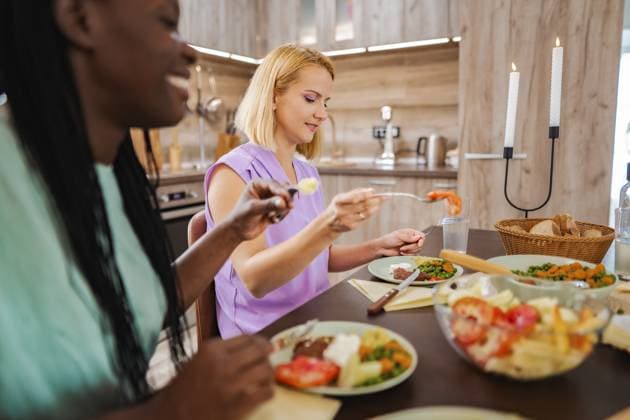 IMAGO Creative, Ostern, Bräuche, Osterbrunch Friends enjoying a delicious homemade meal in a cozy kitchen Two friends savoring a delightful meal around a beautifully set table., model released, , 97514338.jpg RECORD DATE NOT STATED