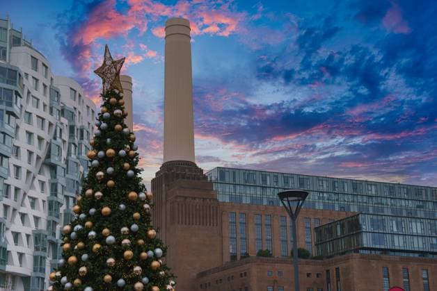 Battersea Power Station with Festive Christmas Tree in London Battersea Power Station s chimneys stand tall against a pink and blue sky, with a large Christmas tree adorned with gold and silver ornaments in the foreground., 64823270.jpg RECORD DATE NOT STATED