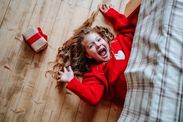 Excited child in red sweater opening Christmas gift indoors at home model released, Symbolfoto property released, MDOF03113