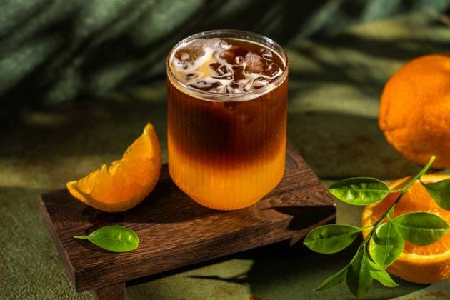IMAGO Creative, Food, Trend, Iced Coffee Iced coffee with fresh orange slice on wooden board Refreshing iced coffee served in a textured glass on a wooden board, accompanied by a fresh orange slice. Perfect for a summer day with vibrant greenery and natural light Model Released Ellsy_ID31375_1067228_007 Copyright: xEllsyx RECORD DATE NOT STATED