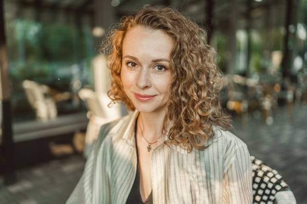 MR_ID31350_22633_AnnaVasileva.jpg A professional woman with curly hair sits in a stylish cafe, showcasing confidence and elegance. The ambient setting complements her poised demeanor, highlighting a modern business lifestyle. Model Released PavelG_ID31350_1066287_031 Copyright: xPavelxGx