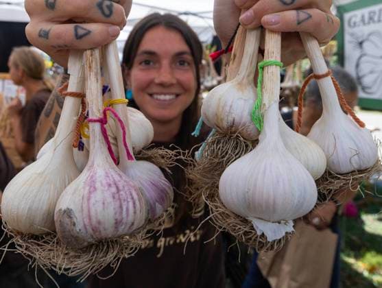 (250929) -- TORONTO, Sept. 29, 2025 -- A woman shows bundles of garlic during the 14th Toronto Garlic Festival in Toronto, Canada, on Sept. 28, 2025. The annual festival was held here on Sunday to celebrate garlic s diverse culinary and cultural uses, with many visitors in attendance. (Photo by Xinhua) CANADA-TORONTO-GARLIC FESTIVAL ZouxZheng 