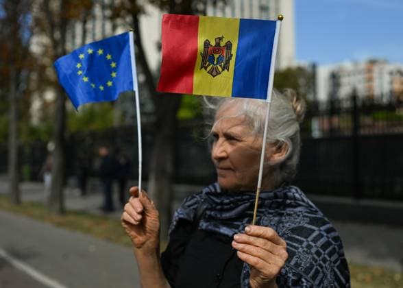 Moldova™s Pro-EU Ruling Party Secures Majority CHISINAU, MOLDOVA - SEPTEMBER 29: A lone pro-EU supporter holds Moldovan and EU flags during a counterprotest as former President Igor Dodon, leader of the pro-Russian Socialist Party, addresses his supporters outside Parliament in Chisinau, Moldova, on September 29, 2025. Final results from the parliamentary election showed the ruling Party of Action and Solidarity (PAS) winning 50.1% of the vote, while the pro-Russian Patriotic Bloc gained 24.2%, securing PAS a decisive majority and strengthening Moldova™s pro-EU course. Chisinau Moldova  Copyright: xArturxWidakx originalFilename: widak-moldovas250929_nphal.jpg