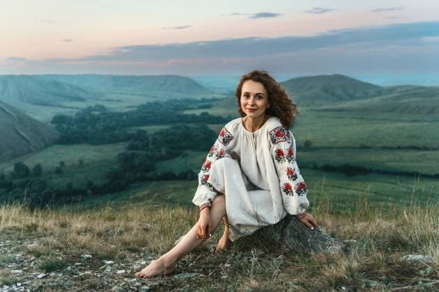 Woman in traditional dress sits barefoot on a mountain top. Andreevka, Orenburg Oblast, Russia R_LQBD250930A-1842651-01 ,model released, Symbolfoto