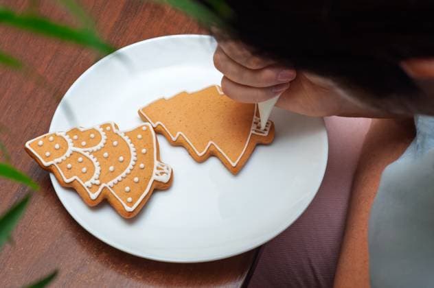 IMAGO Creative, Weihnachten, Food, Backen, Lebkuchen Verzieren von selbstgebackenen Lebkuchen in Form von Weihnachtsbäumen. Hand-piping white icing onto Christmas tree-shaped gingerbread cookies. (License=RF) Copyright: xZoonar.com AndriixAbryutinx 24056052