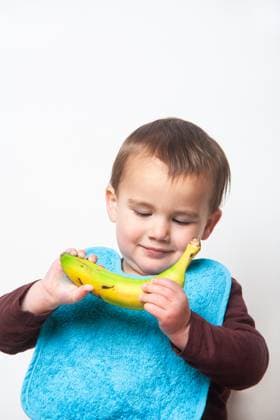 Toddler with bib watching banana being eaten. Children and food. White background Toddler with bib watching banana being eaten. Children and food. White background., model released, , 60317494.jpg RECORD DATE NOT STATED