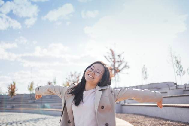 Eine junge Koreanerin lächelt breit und genießt einen sonnigen Tag im Freien. Eine attraktive Asiatin in einem hellen Mantel streckt ihre Arme aus und lacht auf der Straße. A young Korean woman smiles broadly and enjoys a sunny day outdoors. An attractive Asian in a light coat stretches her arms and laughs on the street. The girl stands among the city amphitheater (License=RF) ,model released, Symbolfoto Copyright: xZoonar.com DashaxPetrenkox 23944766 ,model released, Symbolfoto ,property released