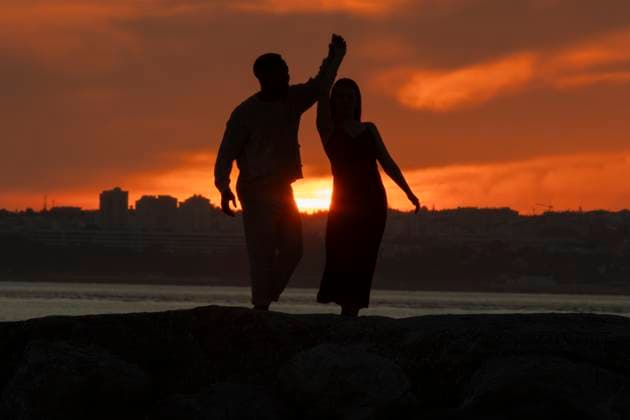 A couple dancing in the sunset A couple dancing in the sunset. The man is holding the woman s hand. The woman is wearing a black dress, model released, , 60122694.jpg RECORD DATE NOT STATED