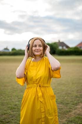 Middle age cheerful woman, wearing yellow dress with headphones Corby, England, United Kingdom R_ATMT2507141B-1779443-01 ,model released, Symbolfoto