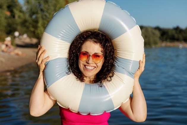 Curly woman smiling with life ring on lake model released, Symbolfoto, MCHF00682