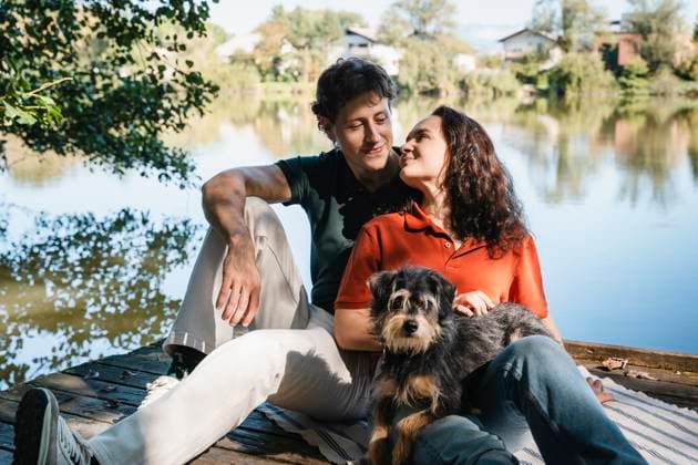 Couple with dog relaxing together outdoors by a lakeside in nature model released, Symbolfoto property released, NDEF02878