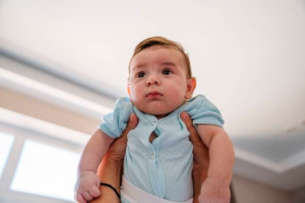 Baby in blue clothing being uplifted with affection indoors model released, Symbolfoto, NLAF00696