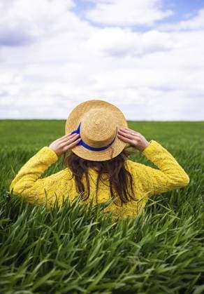 Ein junges Mädchen in einer gelben Jacke hält einen Strohhut vor dem Wind und steht auf einem grünen Weizenfeld, das Mädchen genießt die Natur A young girl in a yellow jacket holds a straw hat from the wind and stands in a green field of wheat, the girl enjoys nature Copyright: imageBROKER SergiyxArtsaba ibxiqx14688116.jpg ,model released, Symbolfoto ,property released
