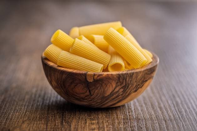 Ungekochte Rigatoni-Nudeln in einer Schüssel auf einem Holztisch. Uncooked rigatoni pasta in bowl on a wooden table. (License=RF) Copyright: xZoonar.com JirixHERAx 24186466