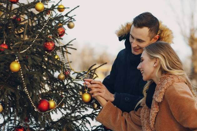 Junges erwachsenes Paar schmückt den Weihnachtsbaum im Winterwald. Konzept zur Feier einer Neujahrsfeier aus Kiefernholz Young adult couple decorates christmas tree in winter forest. New year pine holiday party celebration concept Copyright: imageBROKER Maxx4e ibxiqx15483693.jpg ,model released, Symbolfoto ,property released