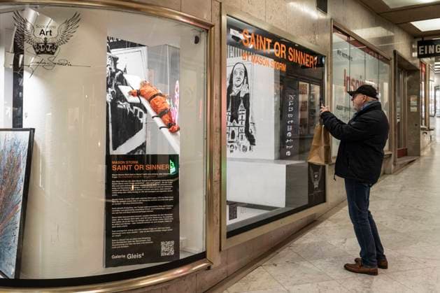November 8, 2025, Basel, Basel-Stadt, Switzerland: A man takes a picture to a sculpture depicting the US President Donald Trump in a prisoner orange jumpsuit and strapped to a cross looking like a death row strapped-down bed, is displayed in a gallery of the city centre of Basel, Switzerland Basel Switzerland - ZUMAp199 20251108_zip_p199_009 Copyright: xMatteoxPlacuccix
