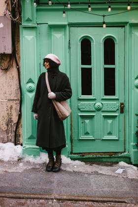 Woman in coat and pink hat smiles with green door in urban setting Québec City, Quebec, Canada CR_WVNP251106-1842431-01 ,model released, Symbolfoto