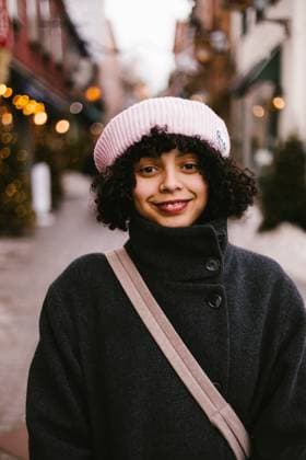 Black hispanic woman in coat and hat on urban street in evening Québec City, Quebec, Canada CR_WVNP251106-1842436-01 ,model released, Symbolfoto