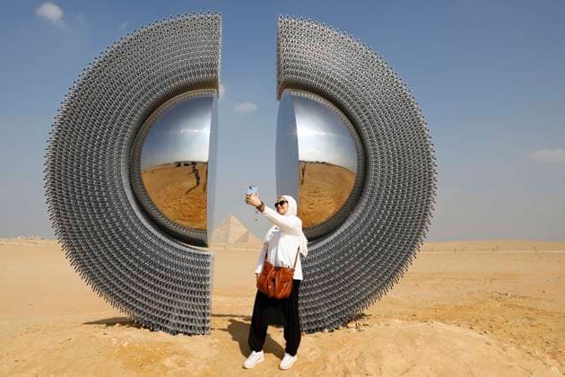 (251111) -- CAIRO, Nov. 11, 2025 -- A visitor takes a selfie in front of an artwork exhibited during the Forever Is Now international art exhibition at Giza Pyramids scenic spot in Giza, Egypt, Nov. 11, 2025. The fifth edition of Forever Is Now international art exhibition on Tuesday kicked off in the area of Egypt s Giza Pyramids scenic spot, showcasing 10 artworks of artists from different countries. The exhibition runs from Nov. 11 to Dec. 6. Ahmed Gomaa) EGYPT-GIZA-PYRAMIDS-ART EXHIBITION-FOREVER IS NOW AixHamaide¡¤gema 