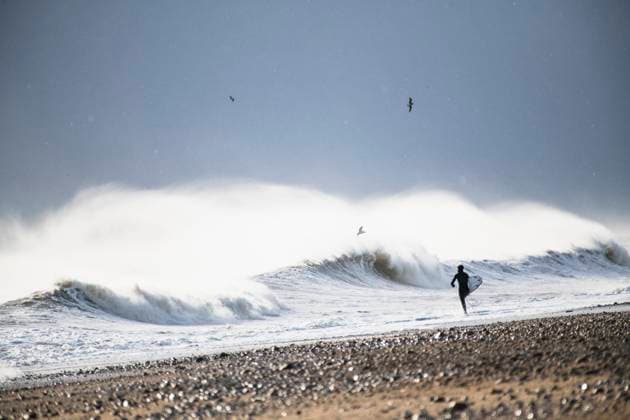 Man going surfing winter waves during snow storm South Kingstown, Rhode Island, United States CR_CABR251110A-1846636-01