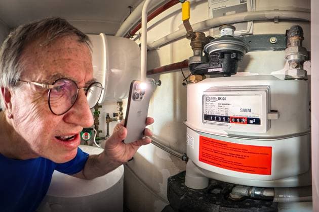 Rentner liest Gaszähler in seinem Heizungsraum ab, Gasheizung in einer Privatwohnung, München, November 2025 Deutschland, München, November 2025, Rentner liest Gaszähler in seinem Heizungsraum ab, leuchtet mit der Handy-Taschenlampe auf den Gaszähler, Energieverbrauch, Gasverbrauch, Erdgasheizung von Viessmann mit Warmwasserspeicher und Wandgerät in einer Privatwohnung, Heizung für Raumtemperatur und Warmwasser, betrieben mit Erdgas, Gas, Heizungsraum, fossile Energien, neue Bundesregierung wollte das Heizungsgesetz abschaffen, Bayern, *** Pensioner reads gas meter in his boiler room, gas heating in a private apartment, Munich, November 2025 Germany, Munich, November 2025, Pensioner reads gas meter in his boiler room, shines his cel
