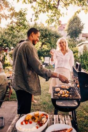 IMAGO Creative, Lifestyle, Feste im Garten #2 Happy man barbecuing while talking with mother in back yard at dinner party Sweden, Stockholm, model released Copyright: xMaskotx , MA120724 MA120724