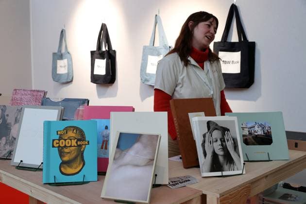 A saleswoman stands before photo books on sale at the 2025 Paris Photo Fair on the opening day at the Grand Palais, on Wednesday, November 12, 2025. The world s most important international photography fair brings together iconic and emerging names, showcasing 179 galleries from 33 countries and a rich programme that encompasses photography in all its forms, from silver gelatin to blockchain.  PAR20251112113 MAYAxVIDON-WHITE