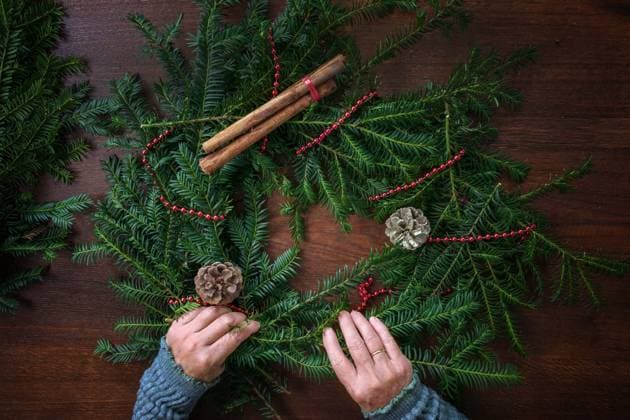 Hände einer reifen Frau beim Arrangieren von immergrünen Zweigen mit Dekorationen für einen Adventskranz, Vorbereitung auf Weihnachten auf einem braunen Holztisch, Draufsicht von oben, ausgewählter Fokus Hands of a mature woman arranging evergreen branches with decorations for an Advent wreath, preparation for Christmas on a brown wooden table, top view from above, selected focus (License=RF) Copyright: xZoonar.com MarenxWinterx 24225004