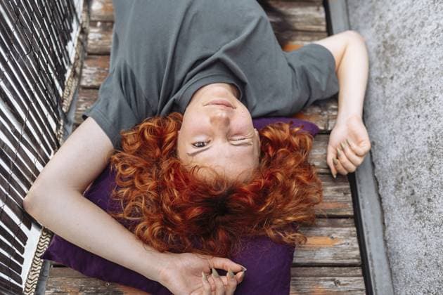 Porträt rothaarige lockige junge Frau, die Entspannung auf Balkon oder Terrasse genießt. rothaarige lockige junge Frau, die auf einem Holzdeckbrett auf dem Balkon liegt und es genießt, nichts zu tun Portrait red-haired curly young woman enjoying relaxation on balcony or terrace. red-haired curly young woman lying on wooden decking board on balcony enjoying doing nothing Copyright: imageBROKER LarysaxStefaniuk ibxiqx15575883.jpg ,model released, Symbolfoto ,property released