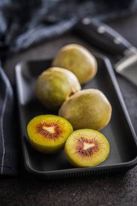 Rote Kiwifrüchte auf einem Teller auf einem schwarzen Tisch. Red kiwi fruit on plate on a black table. (License=RF) Copyright: xZoonar.com JirixHERAx 24239061