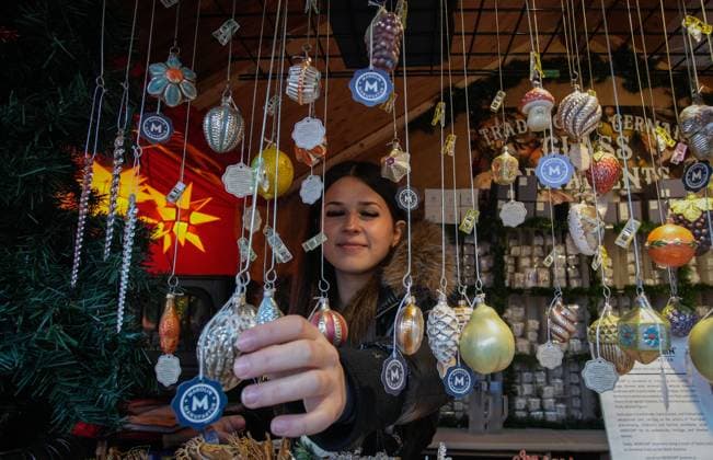 (251115) -- VANCOUVER, Nov. 15, 2025 -- A vendor shows decorative ornaments in a wooden hut at the Vancouver Christmas Market in Vancouver, British Columbia, Canada, Nov. 14, 2025. The annual festive event features more than 110 wooden huts offering various handicrafts, traditional European food, drink, and souvenirs, along with live performances. This year s market opened here on Thursday and will run until Dec. 24. (Photo by Xinhua) CANADA-VANCOUVER-CHRISTMAS MARKET LiangxSen