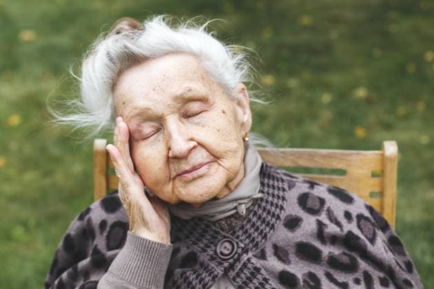 Ältere Frau mit geschlossenen Augen, die ihren Kopf berührt, Müdigkeit oder Unwohlsein ausdrückt, im Freien sitzt, Konzept des Alterns und Gesundheitsbewusstsein Elderly woman with closed eyes touching her head, expressing fatigue or discomfort, sitting outdoors, concept of aging and health awareness Copyright: imageBROKER EvgeniiaxGordeeva ibxiqx15555990.jpg ,model released, Symbolfoto ,property released