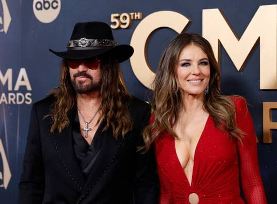 (L-R) Billy Ray Cyrus and Elizabeth Hurley arrive on the red carpet for the 59th CMA Awards in Nashville, Tennessee, on Wednesday, November 19, 2025.  NAS20251119243 JOHNxANGELILLO