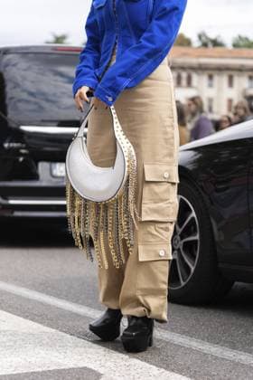 Mailand, Italien 21. September 2022: Frau in asymmetrischer Kurzjacke aus blauem Denim, Ledertasche mit genagelten Nieten, Kettenanhänger, Schulter, beigefarbene Cargo Schlaghose, Plateauschuhe mit hohen Absätzen Milan, Italy - September, 21, 2022: woman in blue denim asymmetric cropped jacket, leather bag with nailed studded fringed chain pendant shoulder, beige cargo flared pants, platform high heels shoes Copyright: imageBROKER IgorxZakirov ibliqx15563483.jpg