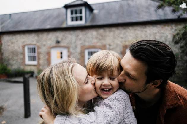 Parents kissing child on cheek showing affection and family joy outdoors model released, Symbolfoto, ASGF07295